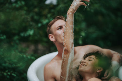 Portrait of shirtless young man looking up outdoors