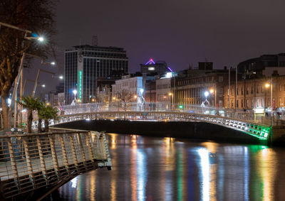 Illuminated bridge over river in city at night