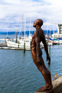 Statue on retaining wall by sea