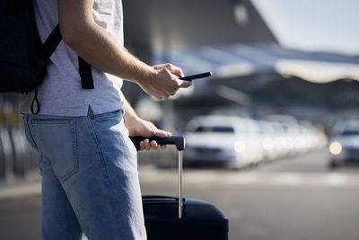 Man holding smartphone and using mobile app against a row of taxi cars. 