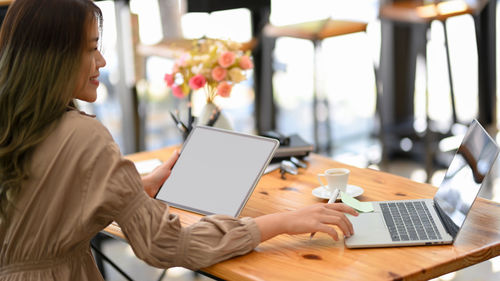 Smiling businesswoman using laptop in cafe