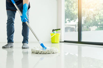 Low section man cleaning floor with mop at home