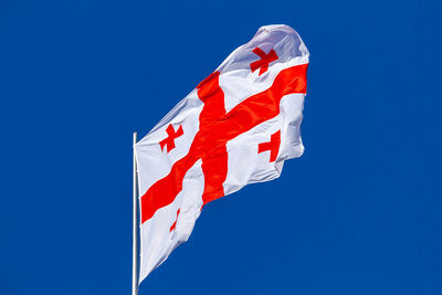 Low angle view of flag against clear blue sky