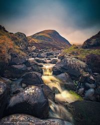 Water flowing through rocks against sky