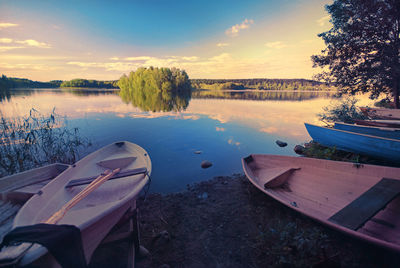 Boats moored in lake against sky during sunset