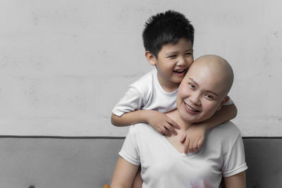 Portrait of father and son against wall