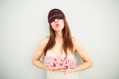 Portrait of young woman standing against white background