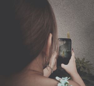 Rear view of girl photographing with mobile phone