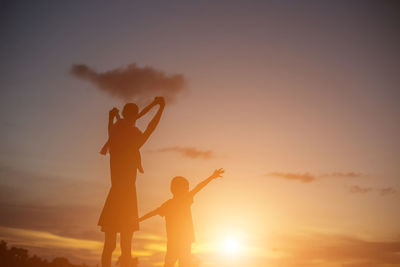 Silhouette friends standing against sky during sunset