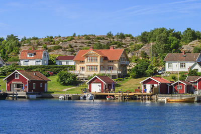 Houses by river and buildings against sky