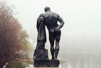 Statue against trees and plants against sky