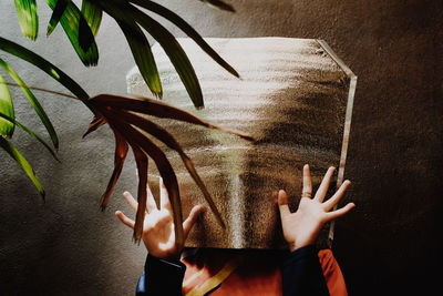 Young woman with obscured face against wall