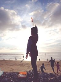 People on beach against sky during sunset