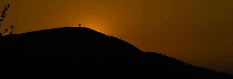 Scenic view of silhouette mountains against orange sky