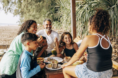 Happy family enjoying food while sitting together in beach hut on vacation