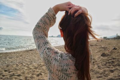 Midsection of woman at beach against sky