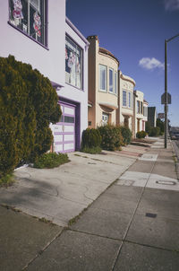 Sidewalk by street in city against sky