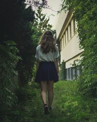 Rear view of woman walking on grass amidst plants