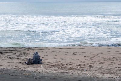 Rear view of people sitting on beach