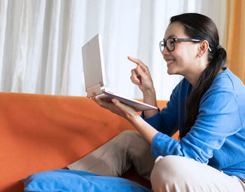Side view of young man using mobile phone while sitting on sofa