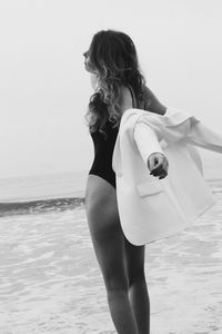 Rear view of young woman standing at beach