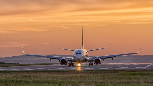 Airplane on field against sky during sunset