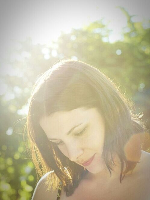 focus on foreground, person, headshot, young adult, portrait, close-up, leisure activity, looking at camera, lifestyles, front view, young women, head and shoulders, day, casual clothing, outdoors, sunlight, side view