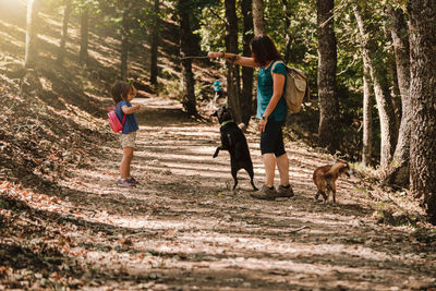 Mother and daughter playing with dogs in forest