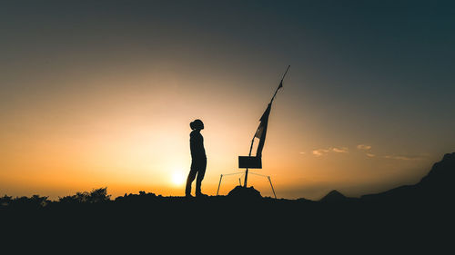 Low angle view of silhouette man standing on field against sky during sunset