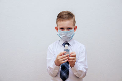 Portrait of boy holding ice cream against white wall