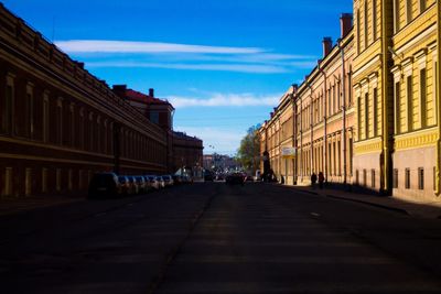 Road amidst buildings in city against sky