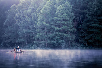 People riding boat on river in forest