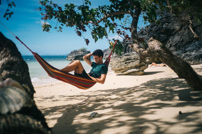 Man sitting on hammock at beach