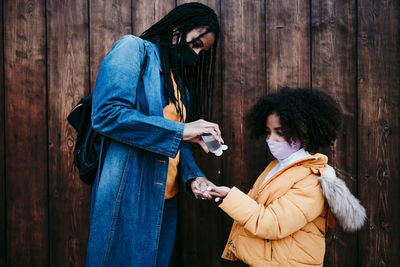 Young couple holding hands standing against wall