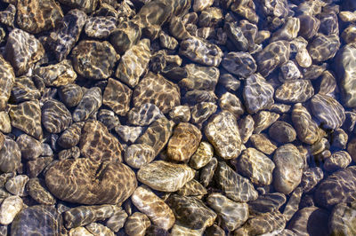 Pebble stone underwater close-up in sunlight. natural background