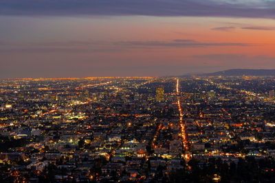Illuminated cityscape against sky at dusk