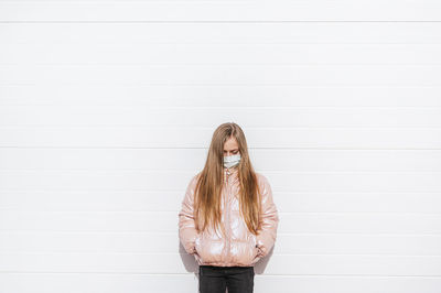 Girl wearing protective face mask standing against wall during covid-19