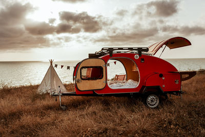 Abandoned car on field against sky