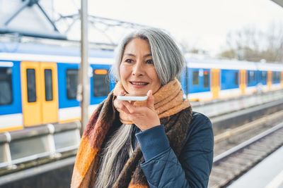 Portrait of young woman standing against train