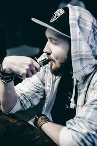 Midsection of man holding camera against black background