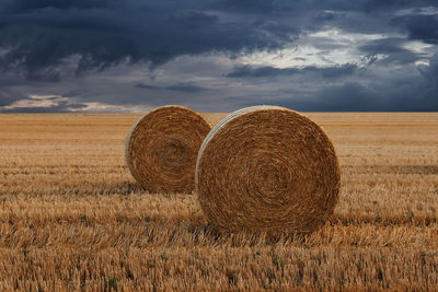 Hay bales on field against sky