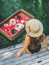 High angle view of woman wearing hat sitting by lake