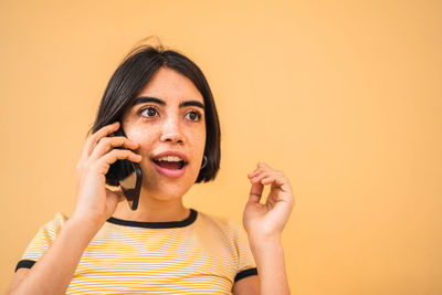 Portrait of young woman using smart phone against gray background