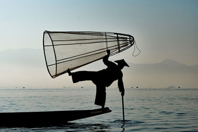 Silhouette of man standing in sea against sky