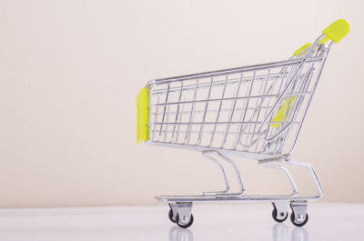 Close-up of shopping cart against gray wall