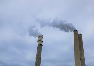 Low angle view of smoke emitting from chimney against sky