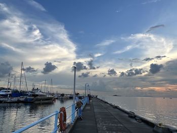 Sailboats moored at harbor against sky during sunset