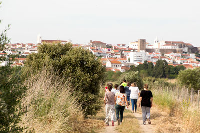 Rear view of men walking on road against sky