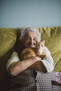 Portrait of happy senior woman cuddling with her cat on the couch