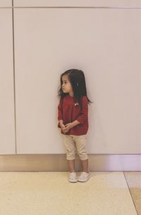 Full length of girl standing against wall